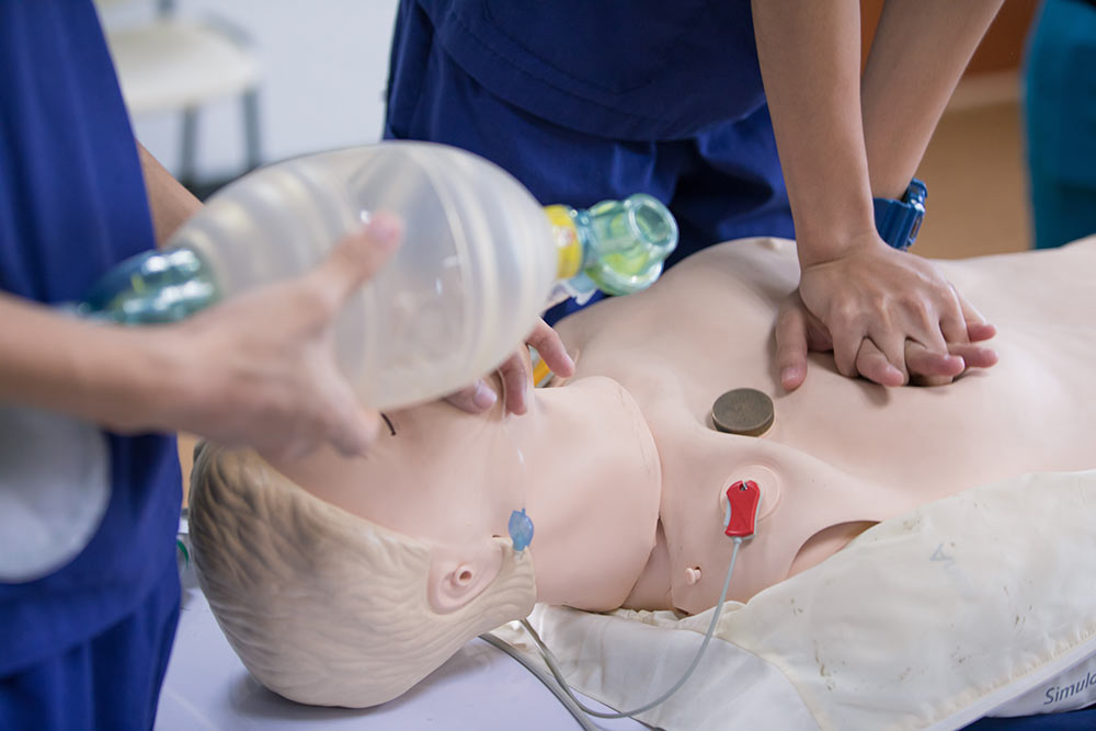 CPR Certification Class - Two people performing CPR on manikin using hands and a bag mask