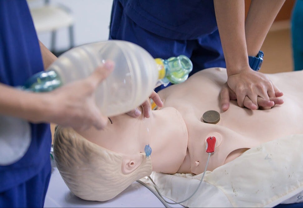 Using Manikins in CPR Training - Nurses performing CPR using hands and airbag device on CPR manikin