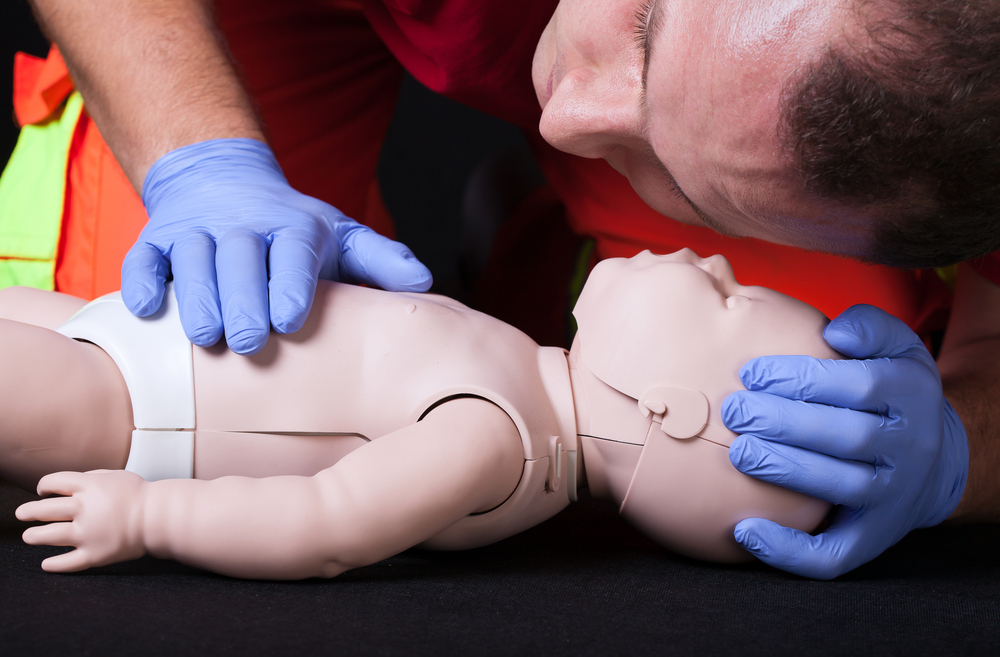 Paramedic demonstrating life function check on infant dummy